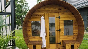 A wooden sauna with a glass door, a towel hanging on the door, and a bench outside. - Riverside Cabin 4
A serene riverside getaway (Campbellford)