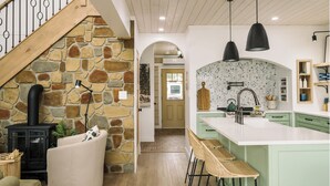 A modern kitchen with a stone wall, wooden staircase, and a central island with bar stools. - Riverside Cabin 4
A serene riverside getaway (Campbellford)