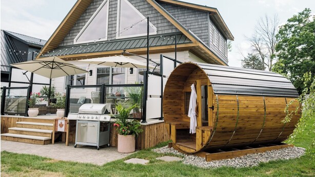 A modern house with a large wooden sauna, a barbecue area, and a covered patio with a table and chairs. - Riverside Cabin 4
A serene riverside getaway (Campbellford)
