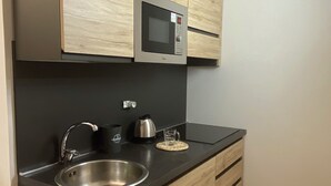 A kitchen with a stainless steel sink, a microwave, and wooden cabinets. - Under Trastevere stars - Live like a local on Gianicolo hill! (Roma)