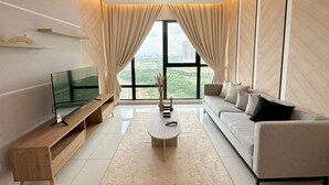 Una sala de estar moderna con un televisor sobre un mueble de madera, un sofá, una mesa de centro y un ventanal con cortinas.