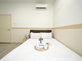 Camera d'albergo con un letto, un comodino con una lampada e un condizionatore d'aria a parete.