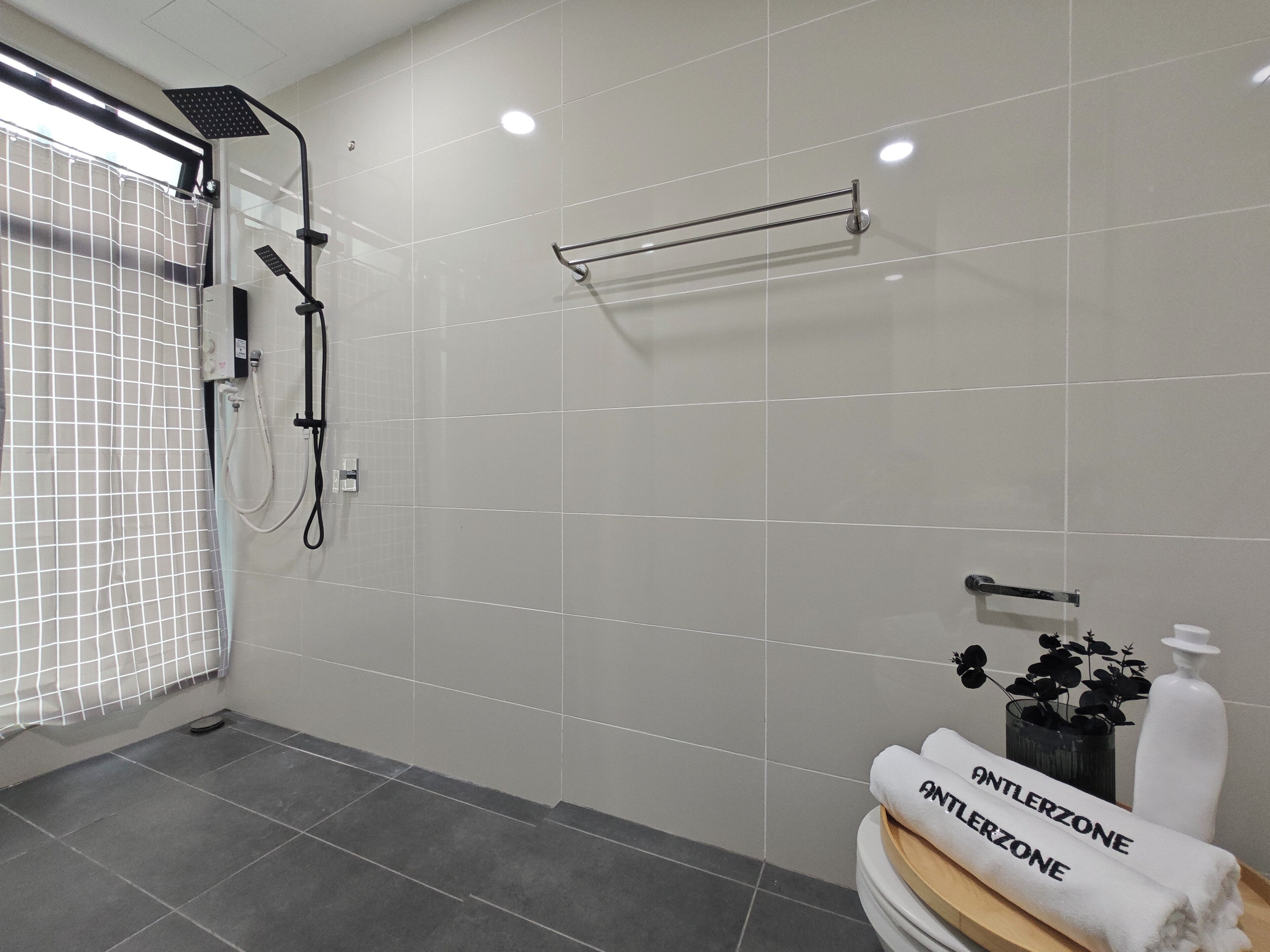 Un baño moderno con ducha, toallero y lavabo con una botella de jabón.
