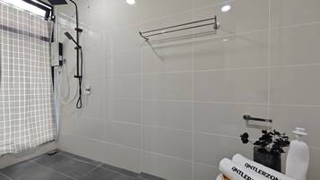 Un baño moderno con ducha, toallero y lavabo con una botella de jabón.