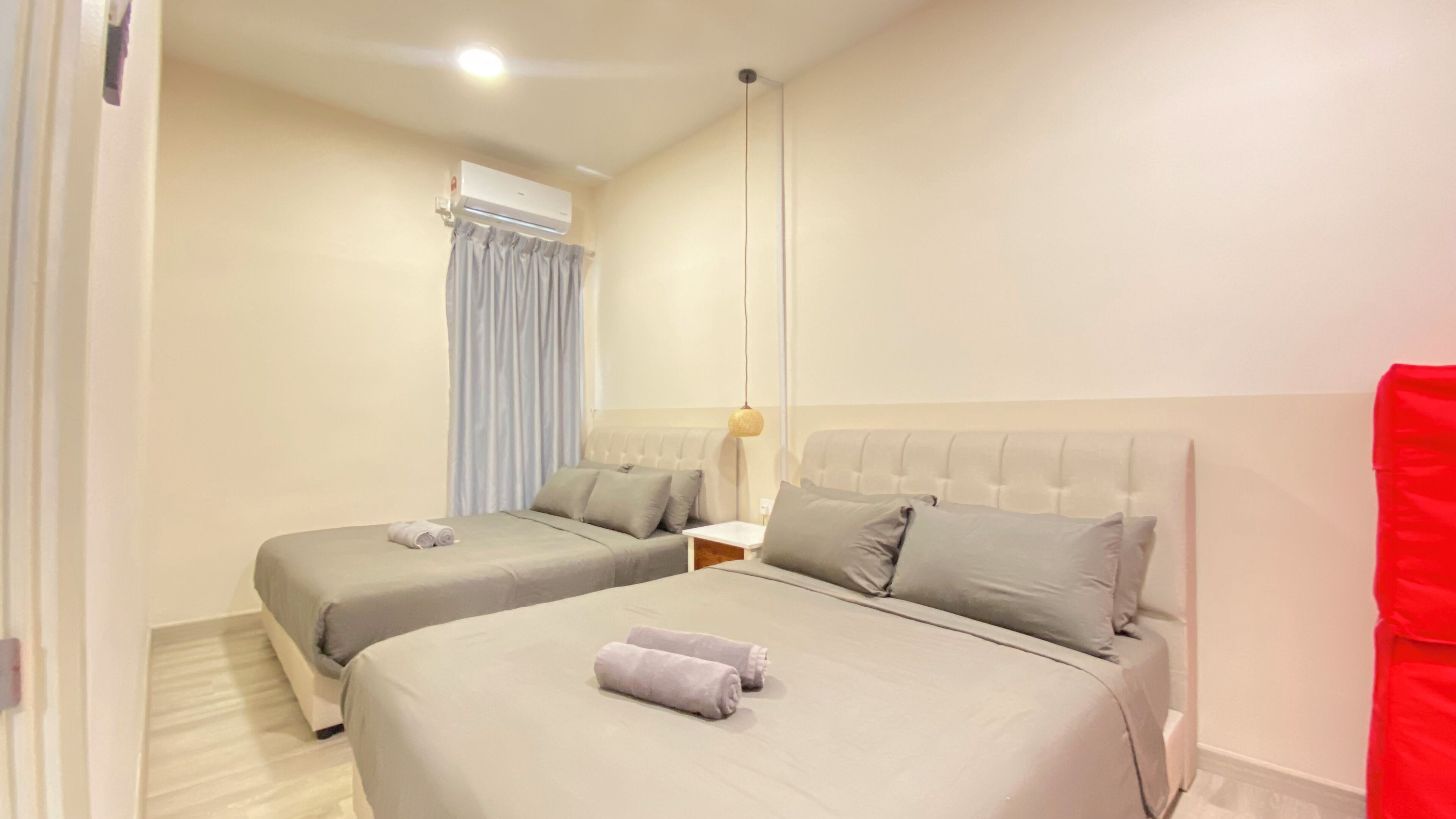 Quarto de hotel com duas camas, um ventilador de teto e uma janela com cortinas.
