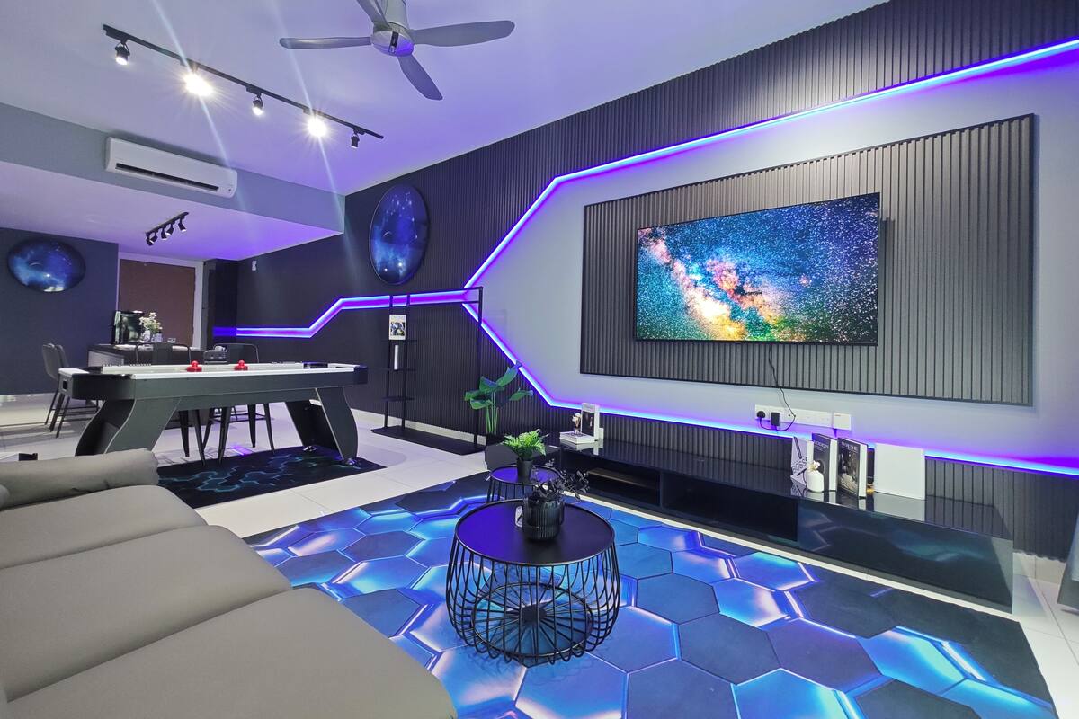 A modern living room with a large flat-screen TV, a ceiling fan, and a hexagonal patterned floor.