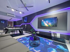 A modern living room with a large flat-screen TV, a ceiling fan, and a hexagonal patterned floor.