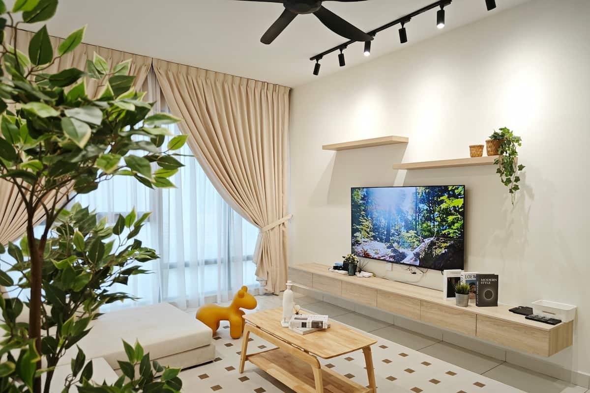 A modern living room with a large flat-screen TV, a sofa, a coffee table, and a potted plant.
