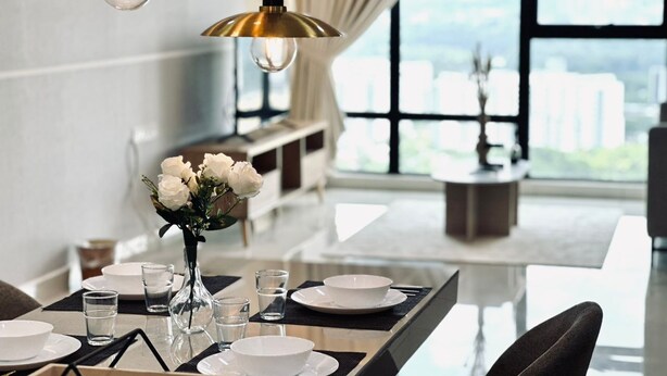 Un comedor moderno con una mesa dispuesta para cuatro personas, un jarrón de flores blancas y vistas a la ciudad a través de amplias ventanas.
