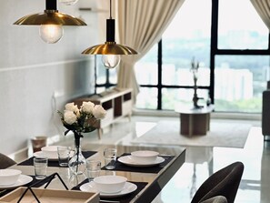Un comedor moderno con una mesa dispuesta para cuatro personas, un jarrón de flores blancas y vistas a la ciudad a través de amplias ventanas.
