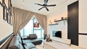 Una sala de estar moderna con un sofá de cuero negro, un mueble blanco para entretenimiento y un ventilador de techo.