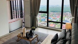 Habitación de hotel moderna con un ventanal amplio que ofrece vista a la ciudad, una bañera, un sofá y una mesita con artículos de aseo.