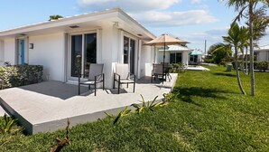 Una casa moderna con un patio, mobiliario exterior y un césped cuidado.