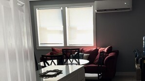 A compact kitchen with a white countertop, a stainless steel sink, and a red chair. There is a window with blinds, a ceiling fan, and a patterned rug on the floor. - Cozy, peaceful, very clean, you can work or just get away, weekly or monthly.   (Jacksonville)