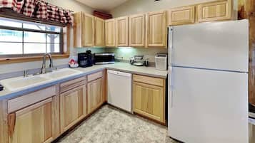 A kitchen with wooden cabinets, a white refrigerator, a sink, a microwave, and a coffee maker.