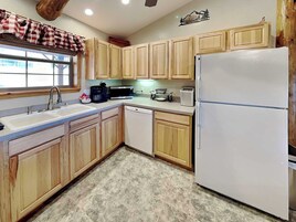 A kitchen with wooden cabinets, a white refrigerator, a sink, a microwave, and a coffee maker.