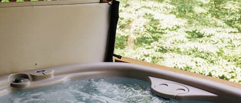 A hot tub with a wooden lattice backdrop and a view of lush greenery.