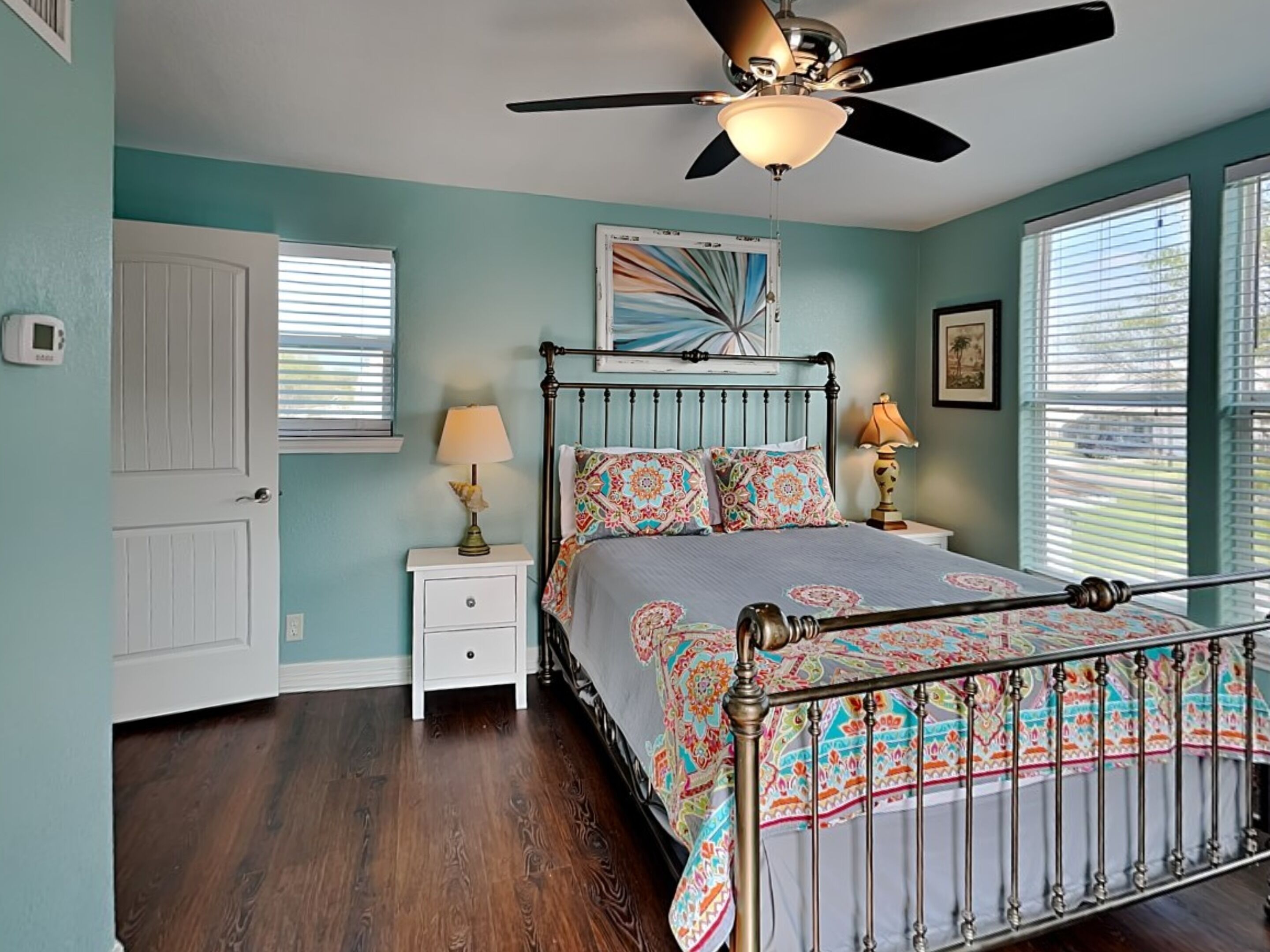 A bedroom with a bed, a ceiling fan, a nightstand, and a window.