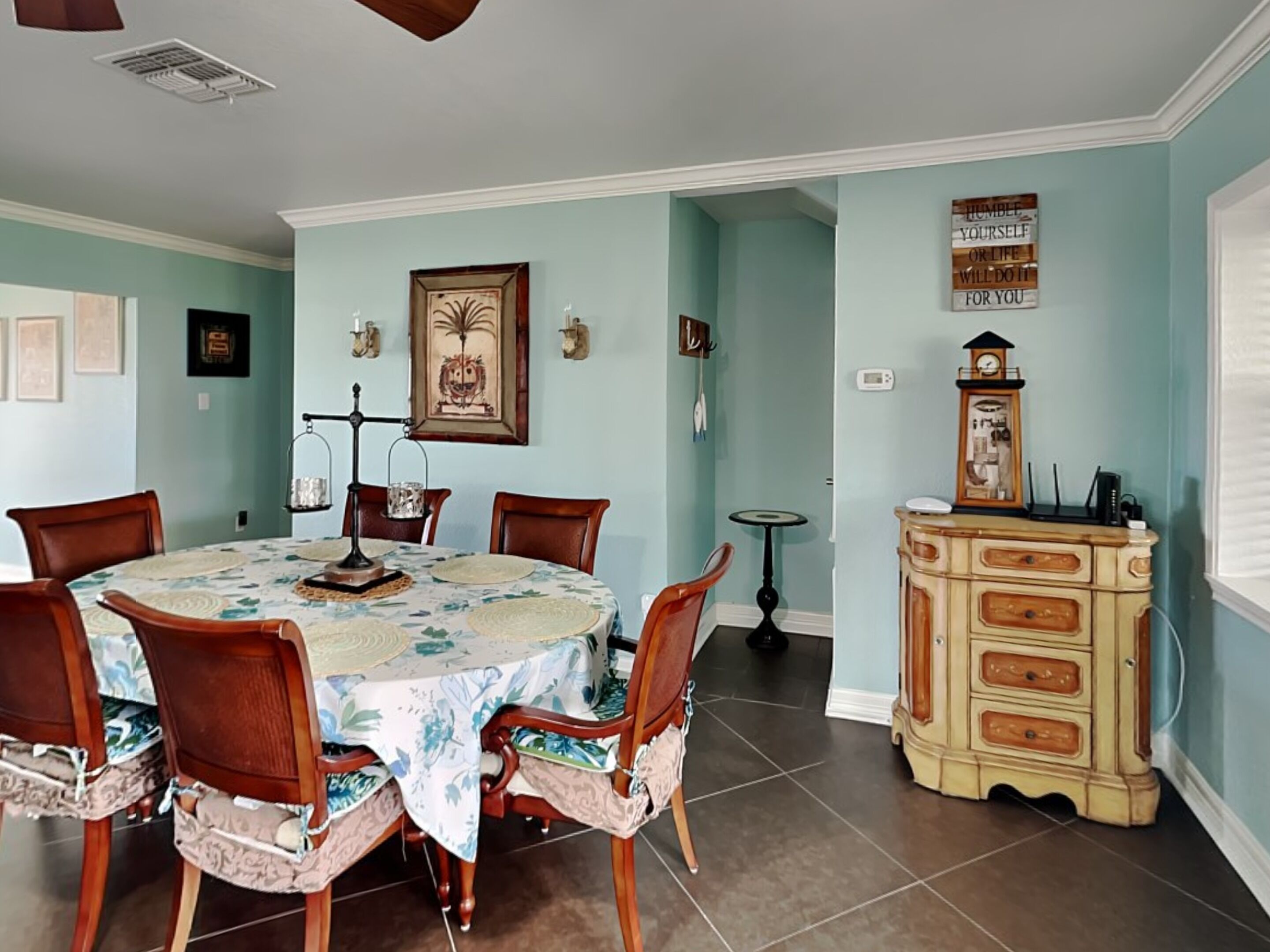 Un comedor con una mesa redonda, sillas, un reloj y un aparador.