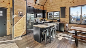 A modern kitchen with a central island, stainless steel appliances, and a large window offering a view of the surrounding area.