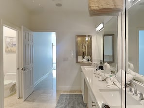 A modern bathroom with a large mirror, two sinks, and a shower. - Brightwater 203 by Distinctive Beach Rentals (Clearwater Beach)