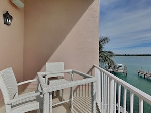 A balcony with wicker furniture and a view of the water. - Brightwater 203 by Distinctive Beach Rentals (Clearwater Beach)