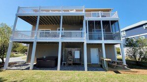 A two-story house with a balcony on the upper floor, a covered porch, and a small outdoor seating area. - "Gay Dayz"4 bed/3.5bath w/pool/beach access (North Topsail Beach)