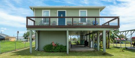 A two-story building with a covered patio area and a fenced yard.