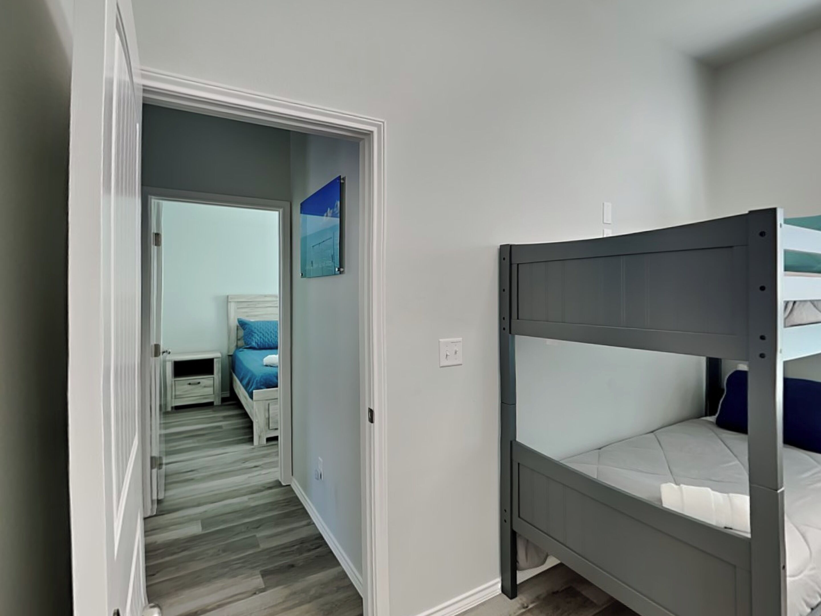 A room with a bunk bed, a nightstand, and a bed with a blue pillow.