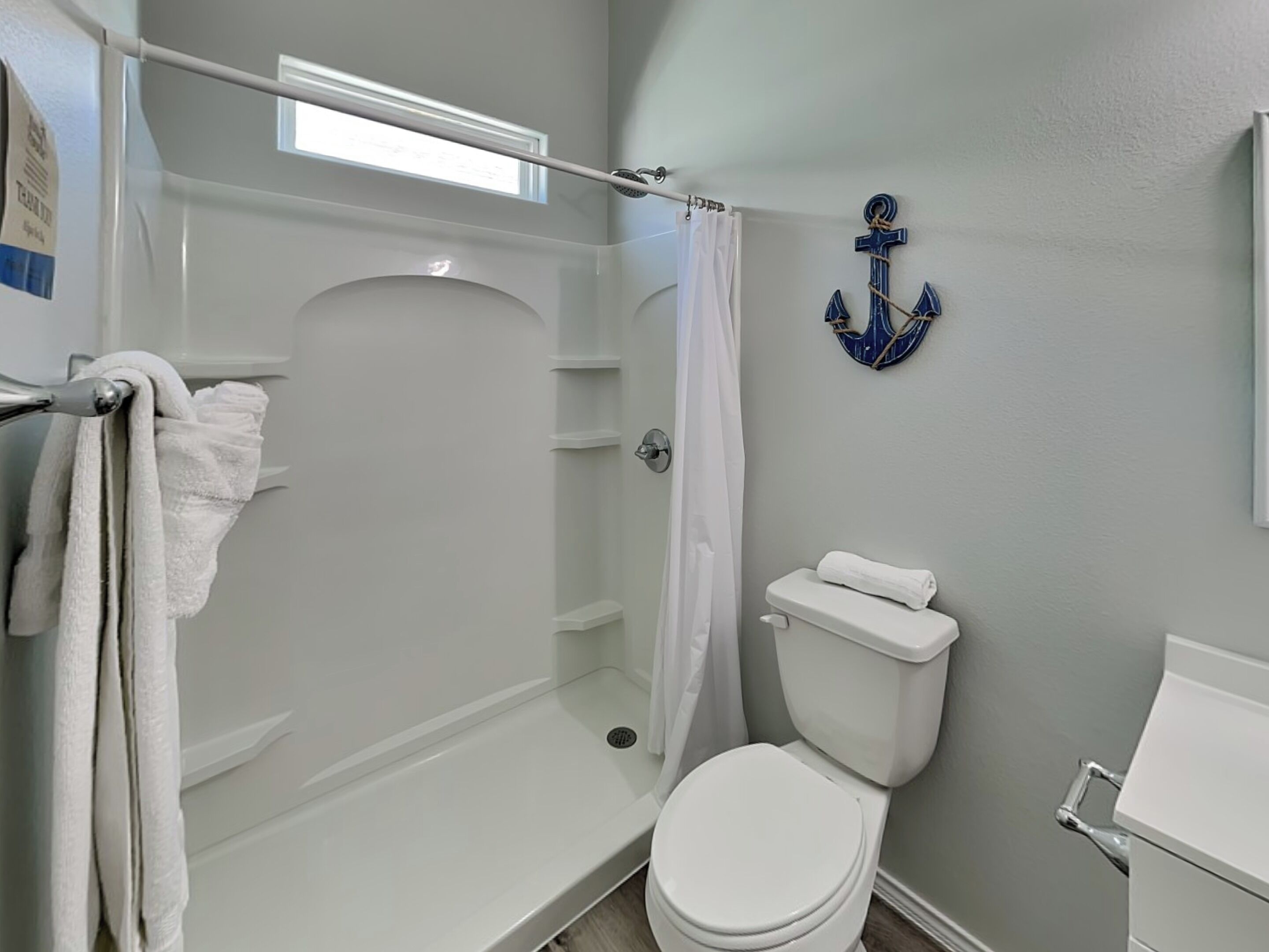 A bathroom with a shower, toilet, and a towel rack.