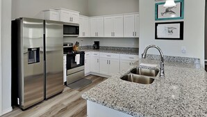 Eine moderne Küche mit weißen Schränken, Edelstahlgeräten, Granit Arbeitsplatten und einer Spüle.