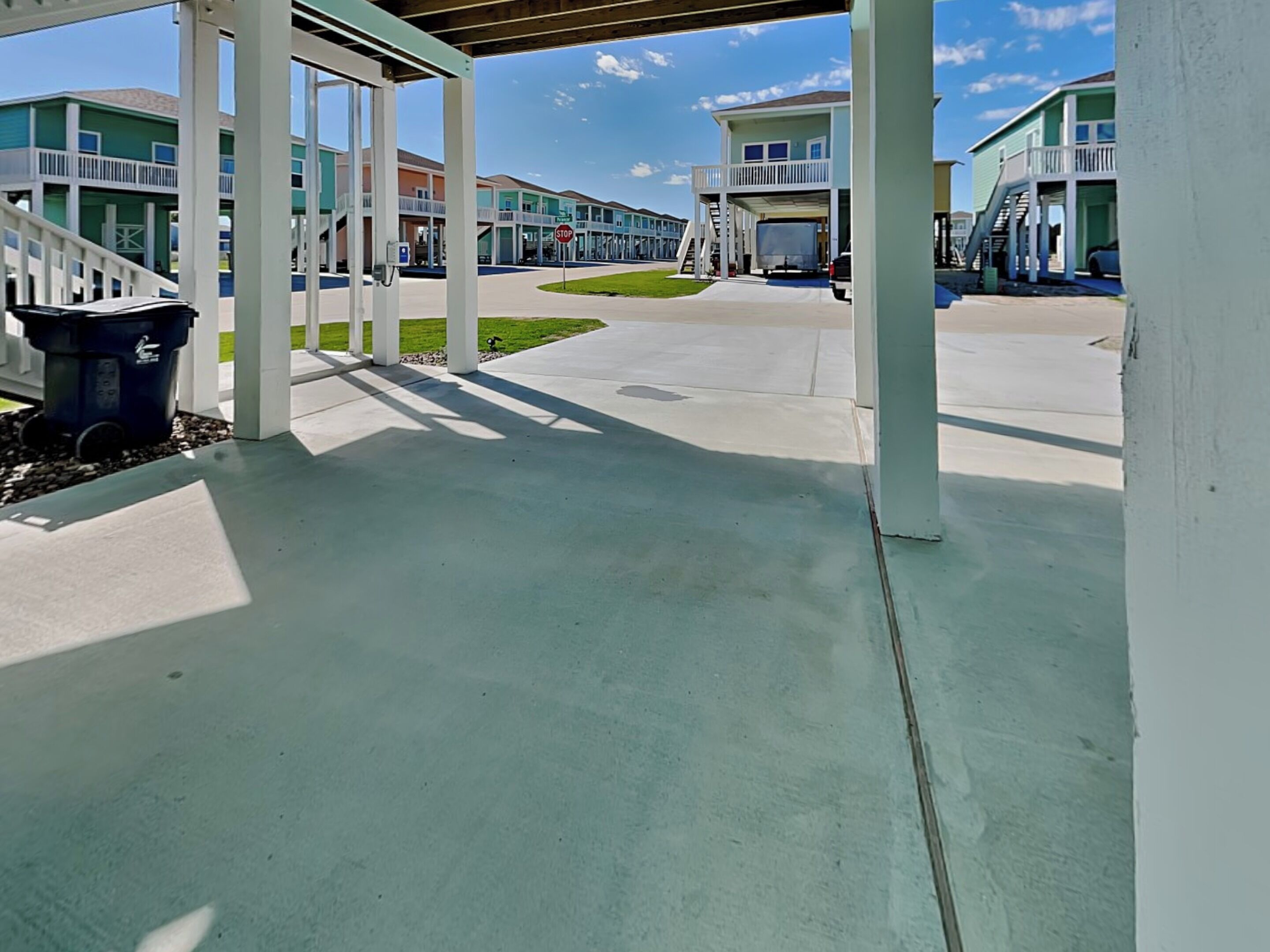 A covered outdoor area with a concrete floor, white columns, and a stop sign.