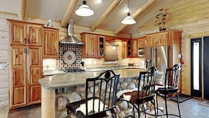 A spacious kitchen with wooden cabinets, a stone island, and a large stove. - Double Eagle Manor by Ruidoso Vacation Rentals (Alto)