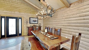 A wooden interior with a large dining table, chairs, and a chandelier. - Double Eagle Manor by Ruidoso Vacation Rentals (Alto)