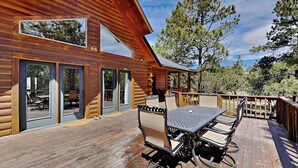 A wooden cabin with a deck, large windows, and outdoor furniture. - Double Eagle Manor by Ruidoso Vacation Rentals (Alto)