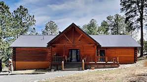 A wooden cabin with a front porch, a garage, and a small driveway. - Double Eagle Manor by Ruidoso Vacation Rentals (Alto)