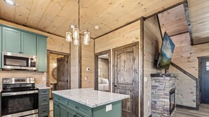 Eine moderne Küche mit Granit Arbeitsplatten, Edelstahlgeräten und einem Kamin aus Naturstein.
