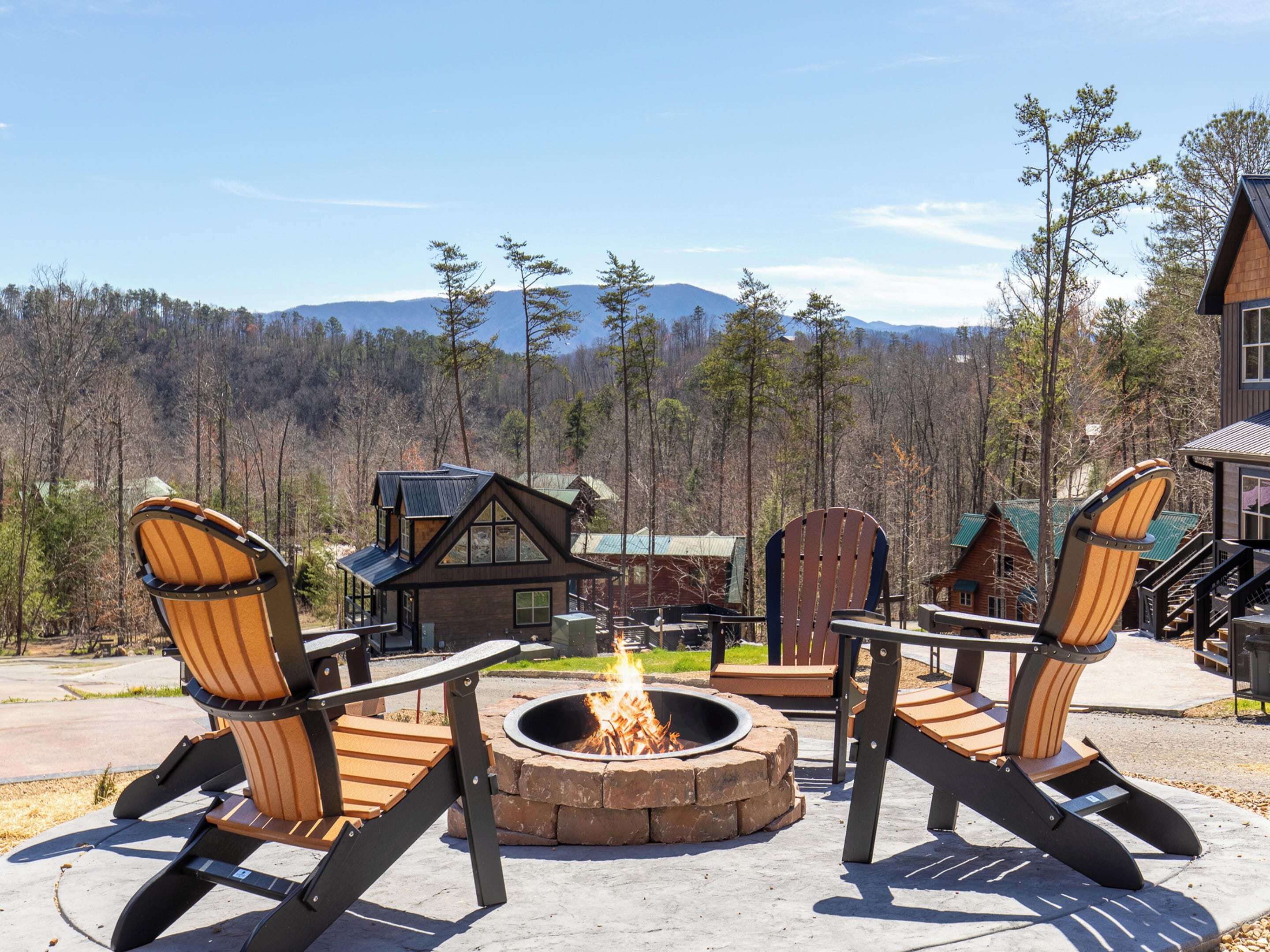 Une cabane avec un foyer et deux fauteuils Adirondack, le tout donnant sur un paysage montagneux.