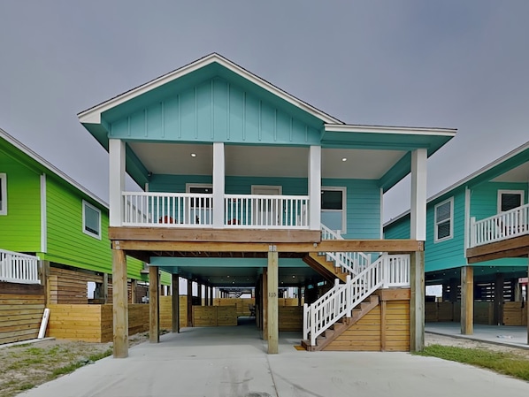 A two-story building with a balcony on the upper floor, wooden deck, and a covered entrance area.