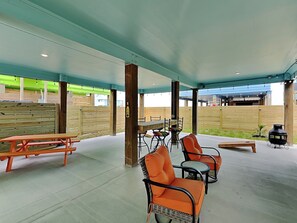 Ein Außenbereich mit einer Terrasse, Picknicktischen, Stühlen und einem Grill.