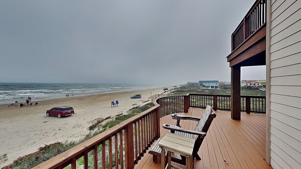 Een houten terras met uitzicht op het strand en de oceaan.