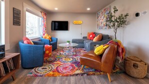 Una sala de estar moderna con un amplio ventanal, un televisor de pantalla plana y decoración colorida.