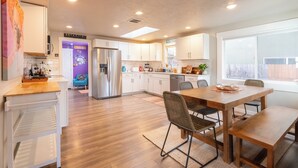 Una cocina moderna con armarios blancos, una mesa de comedor de madera y un refrigerador empotrado.