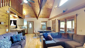 A spacious living area with a wooden ceiling, a dining table, and a kitchen in the background. - Smokey Bear Haven by Jackson Mountain Rentals (Pigeon Forge)