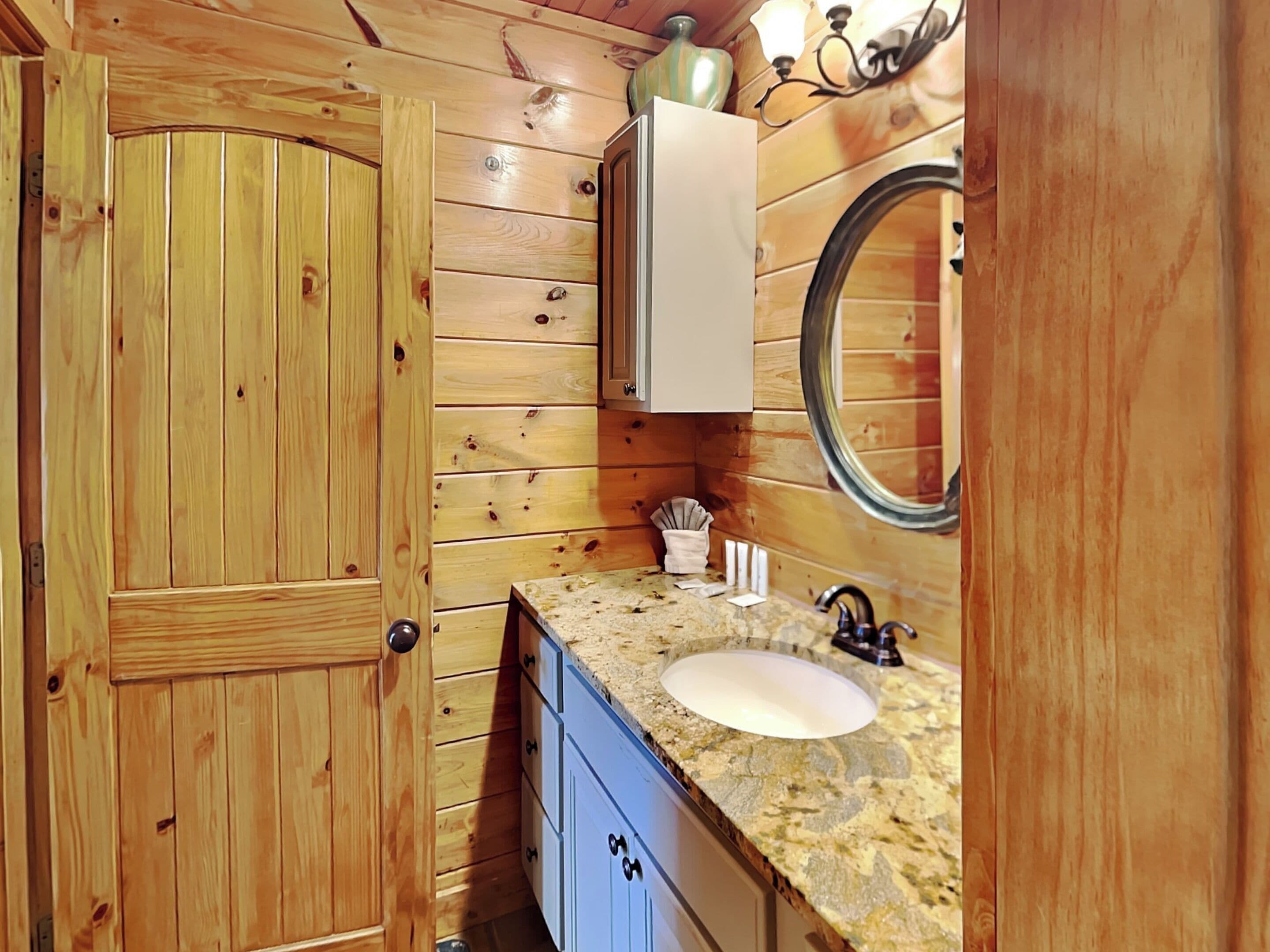 A wooden-paneled bathroom with a sink, mirror, and cabinets.