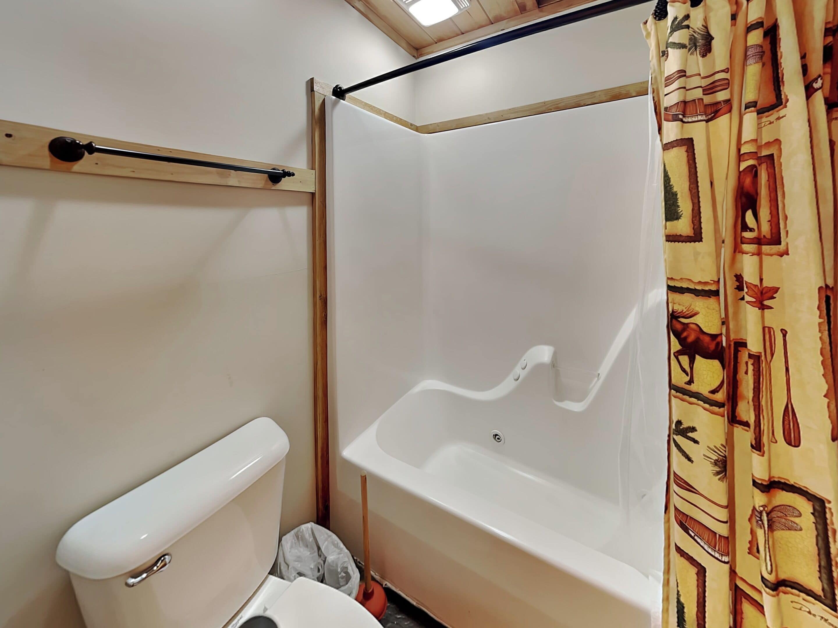 A bathroom with a toilet, a bathtub, and a shower curtain.