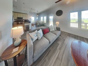 Una sala de estar con un sofá gris, una mesita de madera y un comedor con mesa y sillas.
