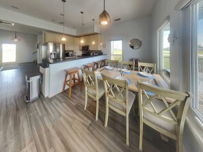 A modern kitchen with a central island, wooden chairs, and a dining table set for six.