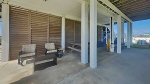Un espacio al aire libre cubierto con piso de concreto, paredes de listones de madera y un banco.