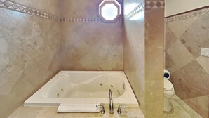 A bathroom with a bathtub, a toilet, and a towel rack. - Sunset On The Seawall #1 by Ryson Vacation Rentals (Galveston)